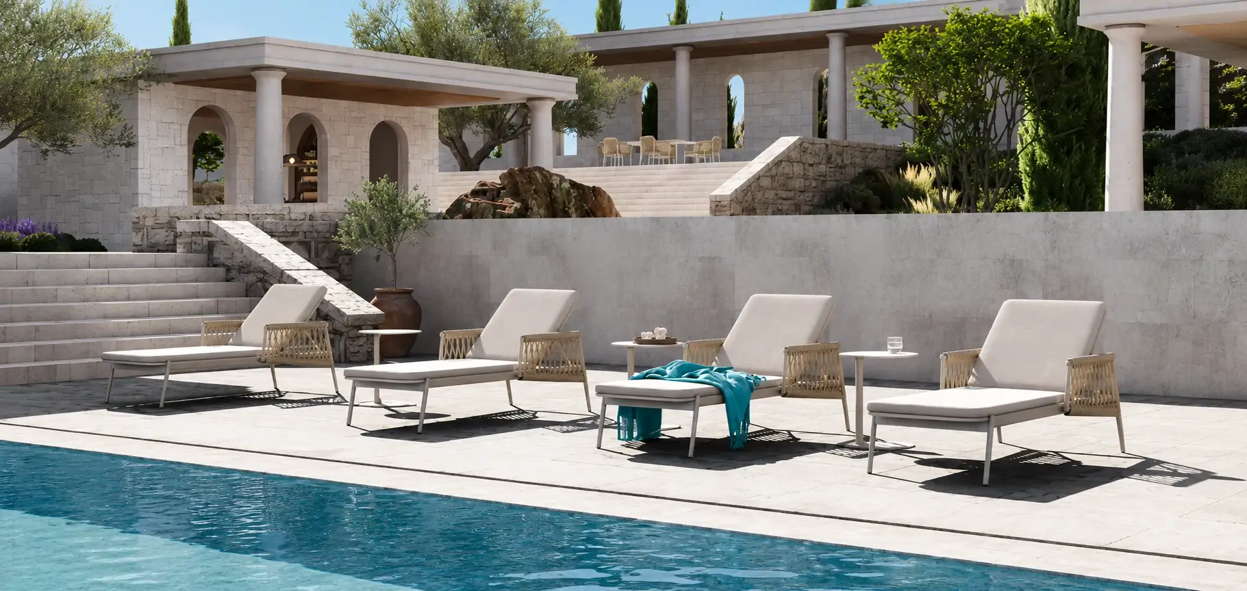 Sun loungers along the edge of a pool below a Mediterranean stone villa