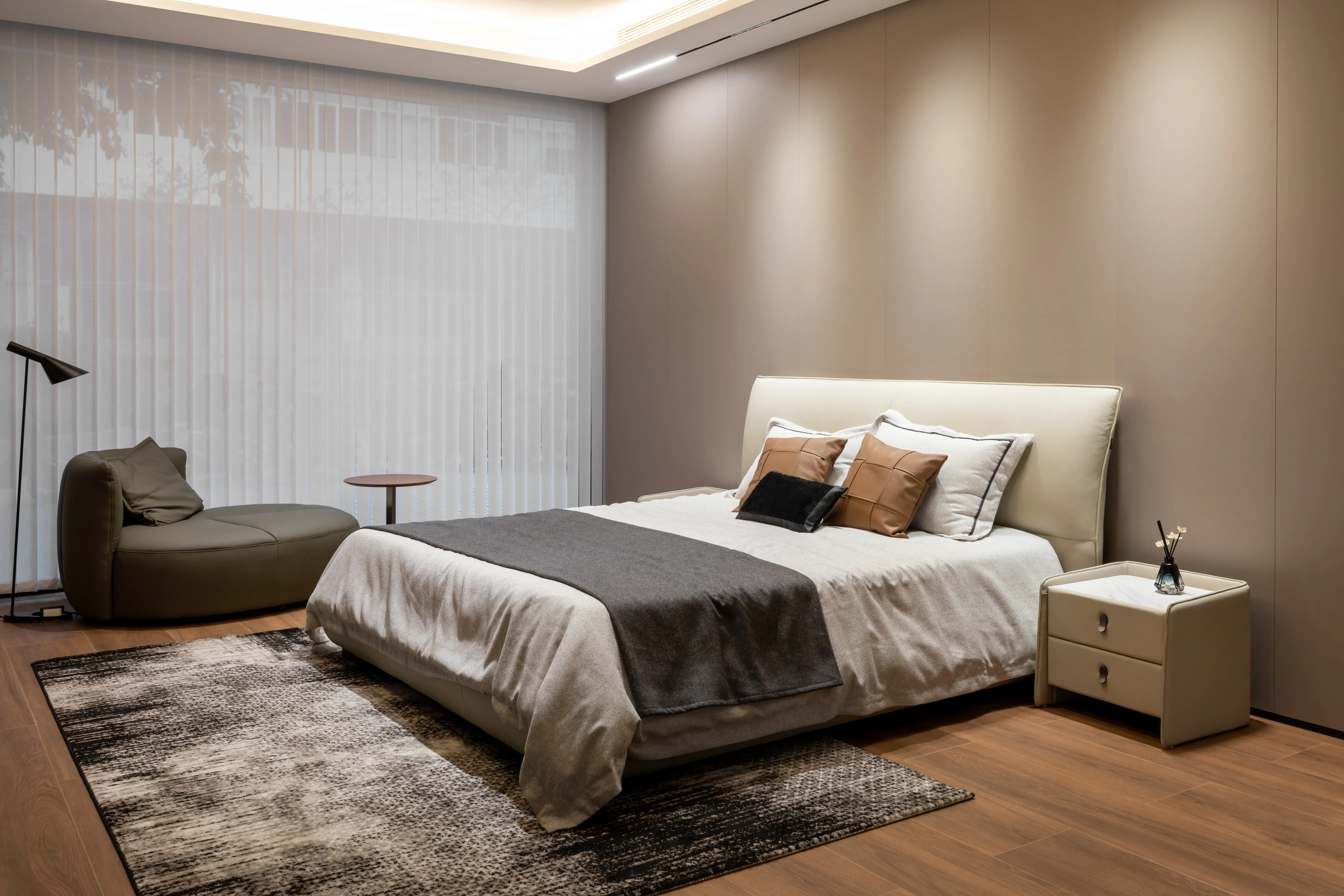 Bedroom with sheer curtains, olive lounge chair and upholstered bed