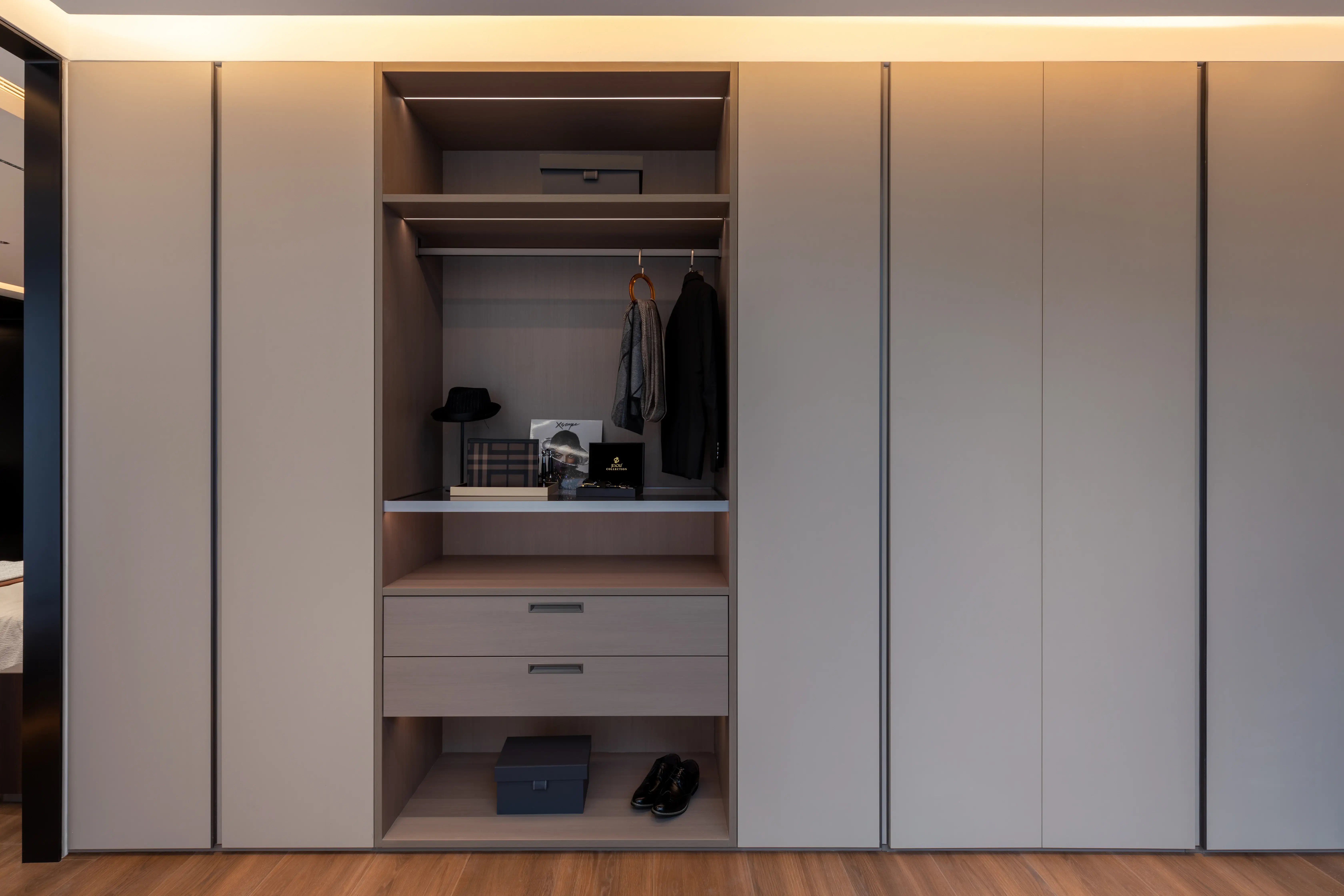Floor-to-ceiling wardrobe wall with an open, illuminated dressing unit